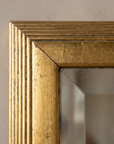 Close-up of the reeded gilt frame corner and beveled glass edge