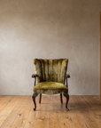 The chartreuse velvet armchair in a wide plaster-walled room with a doorway, showing its real scale