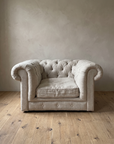 The chesterfield chair from the front, showing the deep diamond tufting, rolled arms, soft seat cushion and buttoned base rail