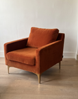 Rust velvet armchair, wide three-quarter view from the left