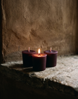 Three votives grouped on a stone ledge, one lit