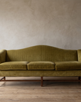 Straight-on front view of the chartreuse camelback sofa showing six mahogany legs and stretchers