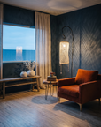 Rust velvet armchair by a linen-curtained window at dusk beside a netted floor lamp and a weathered oak bench