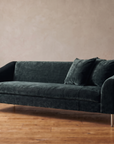 Vanguard Tess sofa in deep peacock crushed chenille with brushed nickel legs, three-quarter view, greige plaster wall and reclaimed wood floor
