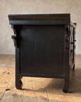Side profile of the black lacquer console showing scroll brackets and hoof feet