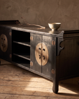 Black lacquer console in warm raking afternoon light with a pale bowl and dried branch on top