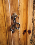 Close-up of the hand-forged iron ring-and-hook latch on knotty pine