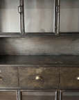 The open steel counter with rounded side galleries between the upper glass doors and the drawers