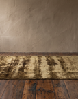Wide room shot of the 59 by 96 inch abstract olive brown rug in front of a lime plaster wall