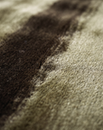 Close-up of the plush silken pile where a dark umber sweep meets khaki olive