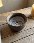 Cream hand thrown ceramic pour bowl with a pulled spout on a weathered wood table