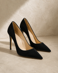 Christian Louboutin Black Suede Pumps, pointed-toe stilettos in black suede on a plaster backdrop