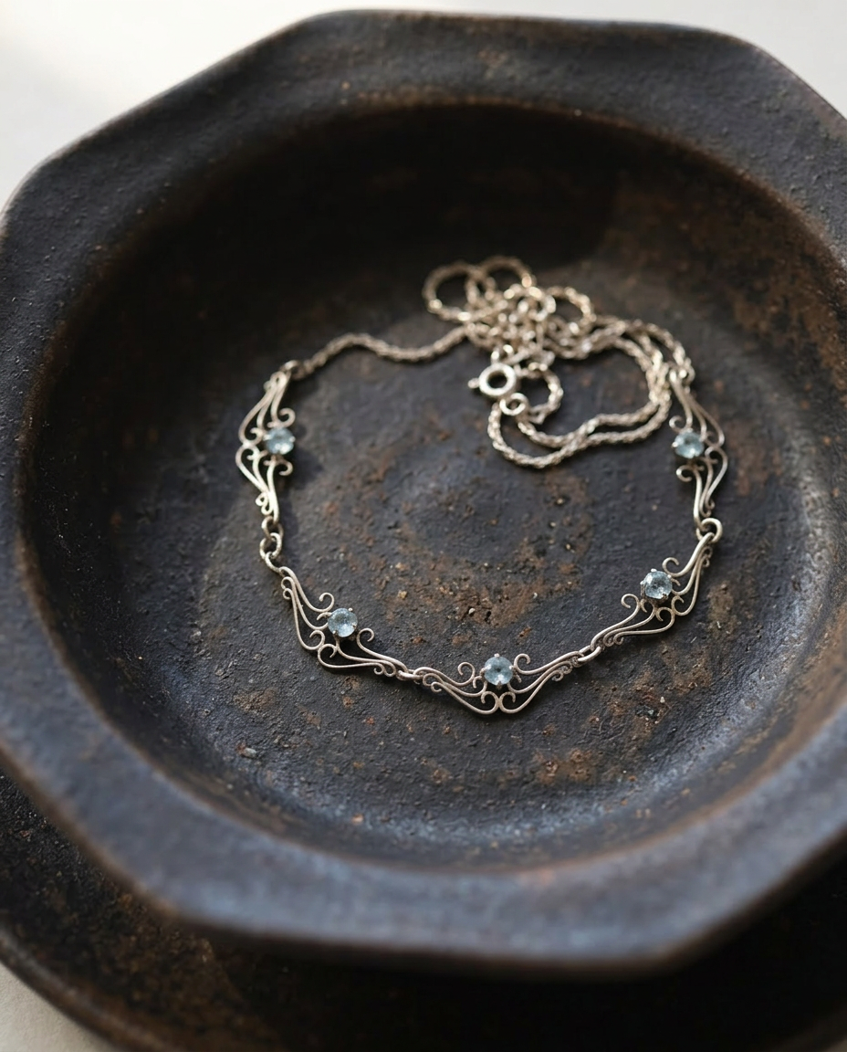 Scrolled Gold Necklace with Five Stones on black ceramic dish
