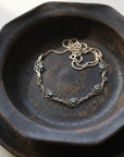 Scrolled Gold Necklace with Five Stones on black ceramic dish