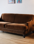 Cognac velvet mid-century sofa, full three-quarter view with lamp and side table