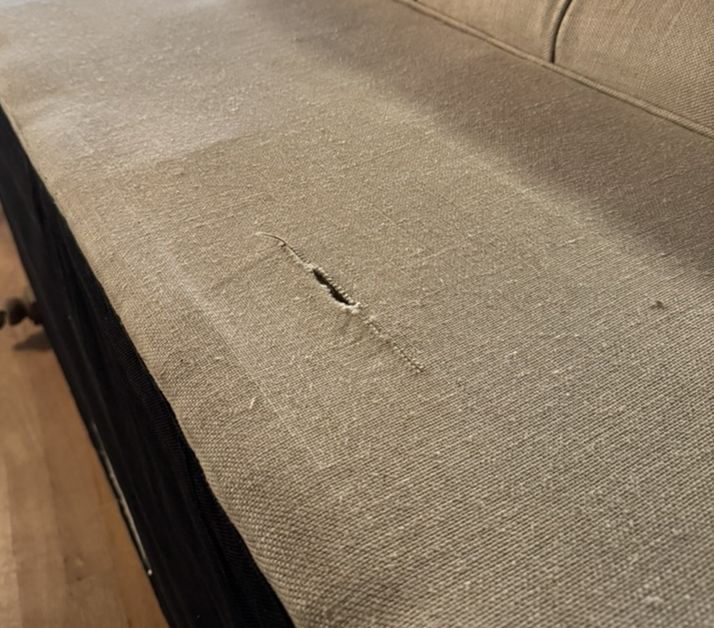 Condition photo: the 3 inch tear in the linen on the outside back panel, a clean slit with the weave intact around it