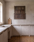 Antique Hoosier Bakers Cabinet hung on a plaster kitchen wall above a limestone counter and stone sink