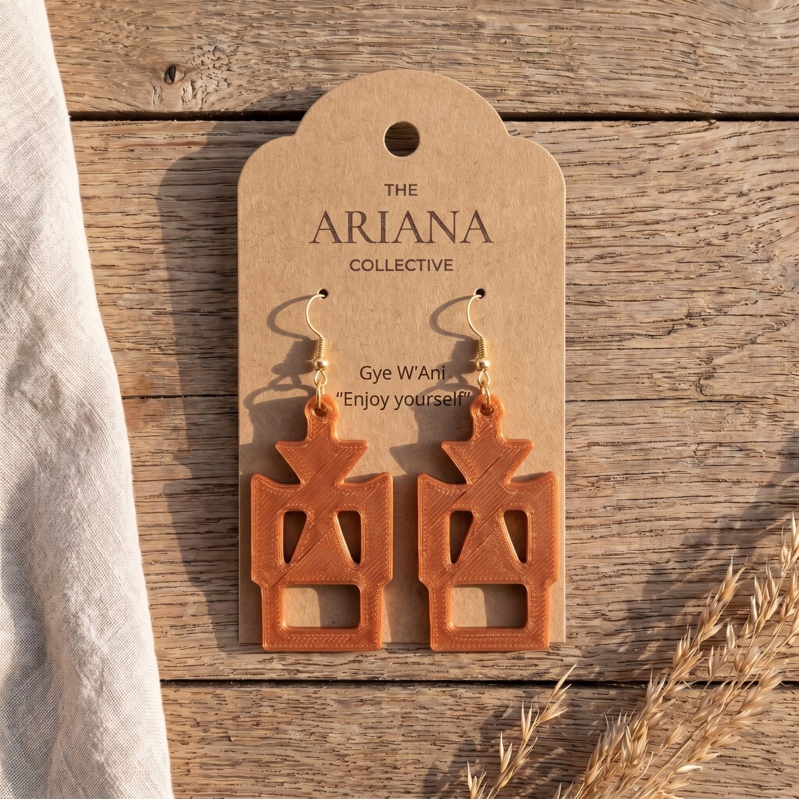 Gye W'Ani Adinkra earrings in copper by The Ariana Collective, on a kraft tag