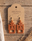 Gye W'Ani Adinkra earrings in copper by The Ariana Collective, on a kraft tag