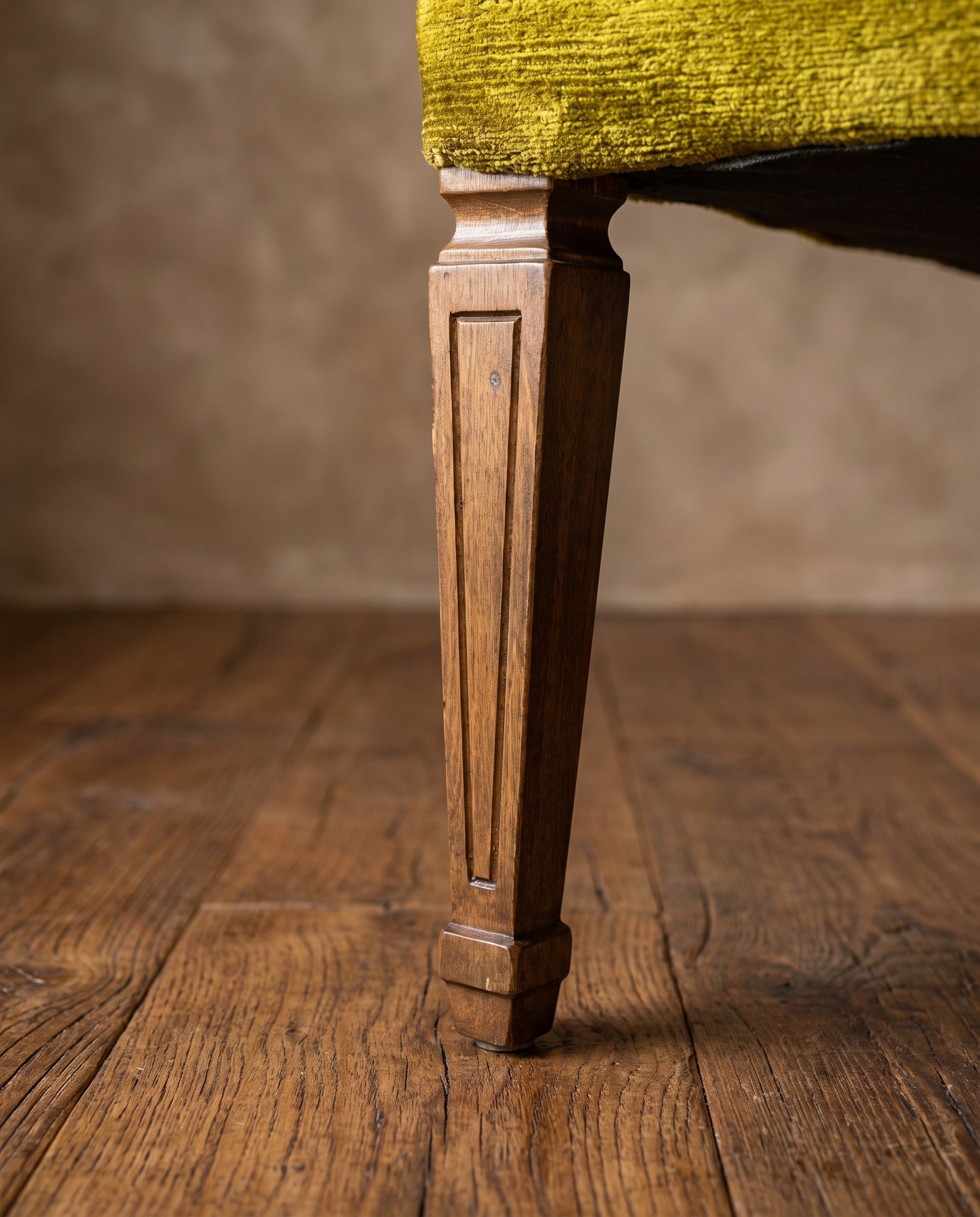 Chartreuse velvet diamond-tufted armchair, full-length macro of one front leg from seat to floor showing fluted carving and cap foot