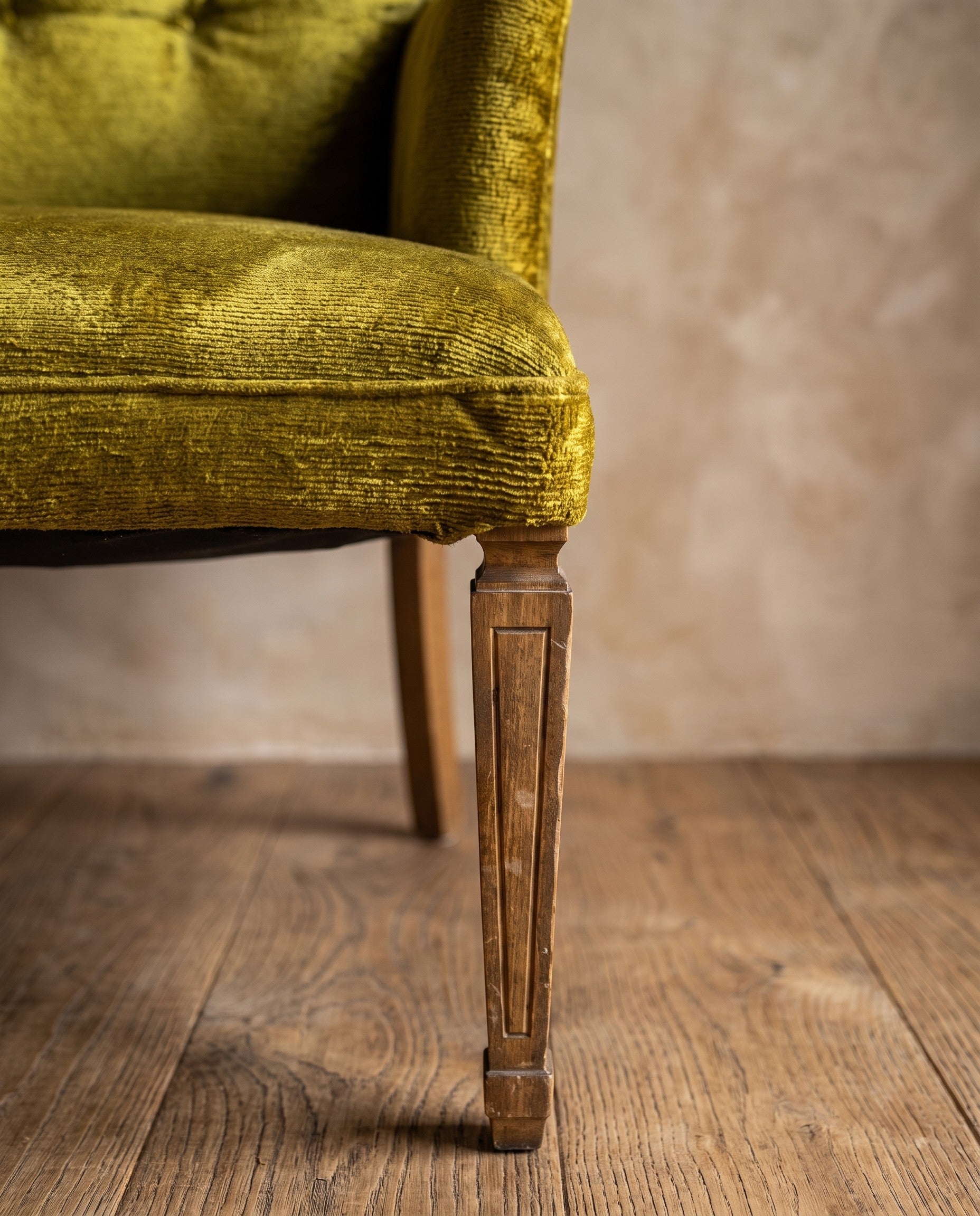 Chartreuse velvet diamond-tufted armchair, macro where the seat's waterfall edge meets the top of the front leg
