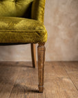 Chartreuse velvet diamond-tufted armchair, macro where the seat's waterfall edge meets the top of the front leg