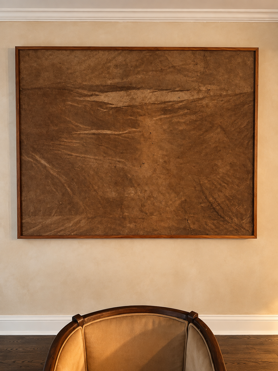 Untitled (Rust) by Nicole Daedone, framed handmade paper in rust and umber tones hung above an armchair