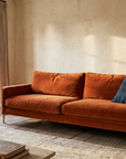 Rust Velvet Track-Arm Sofa, three-quarter view in a sunlit living room