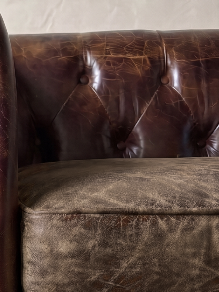 Close-up of the deep diamond button tufting above a crackled smoky brown leather cushion
