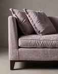 Detail of the arm meeting the bench cushion and dropping to a dark stained tapered block foot