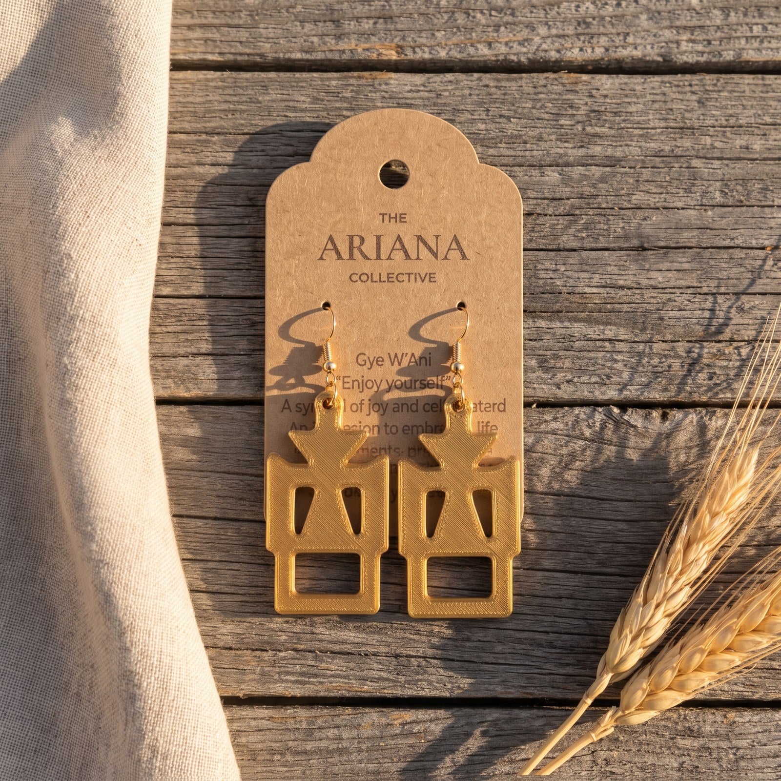 Gye W'Ani Adinkra earrings in gold by The Ariana Collective, on a kraft tag
