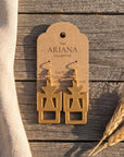 Gye W'Ani Adinkra earrings in gold by The Ariana Collective, on a kraft tag
