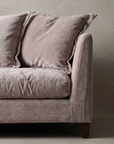 Detail of the slim vertical panel arm with its softly rounded top edge and welt seam, loose back pillows slumped against it