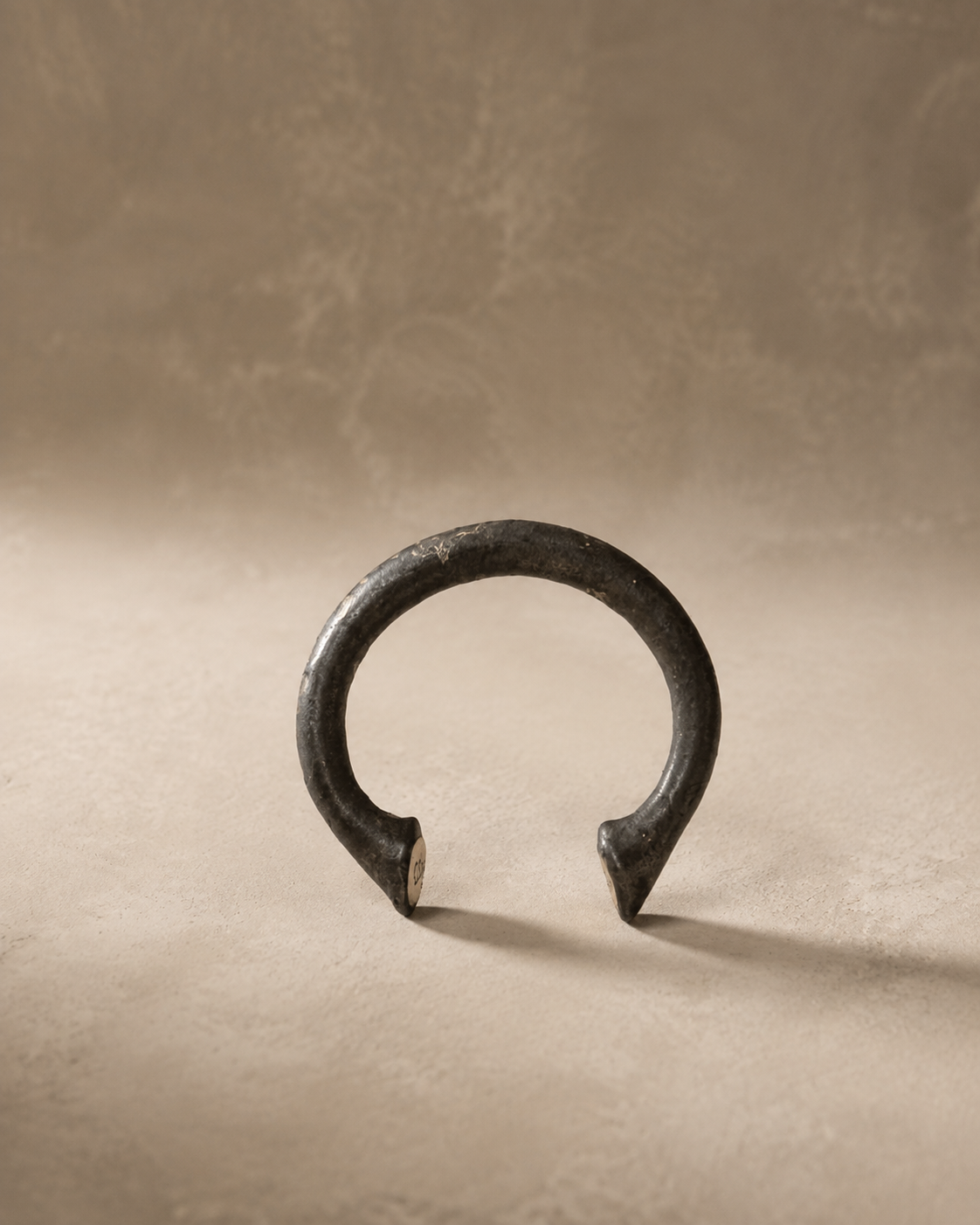 African Currency Bracelet, a dark hand-forged metal manilla cuff with flared ends