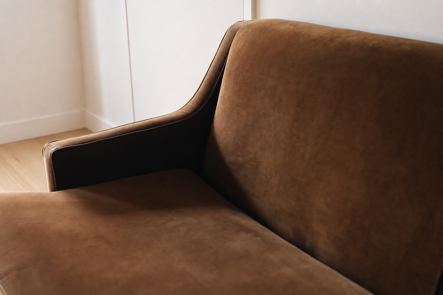 Close-up of the sloped arm and back corner in cognac velvet