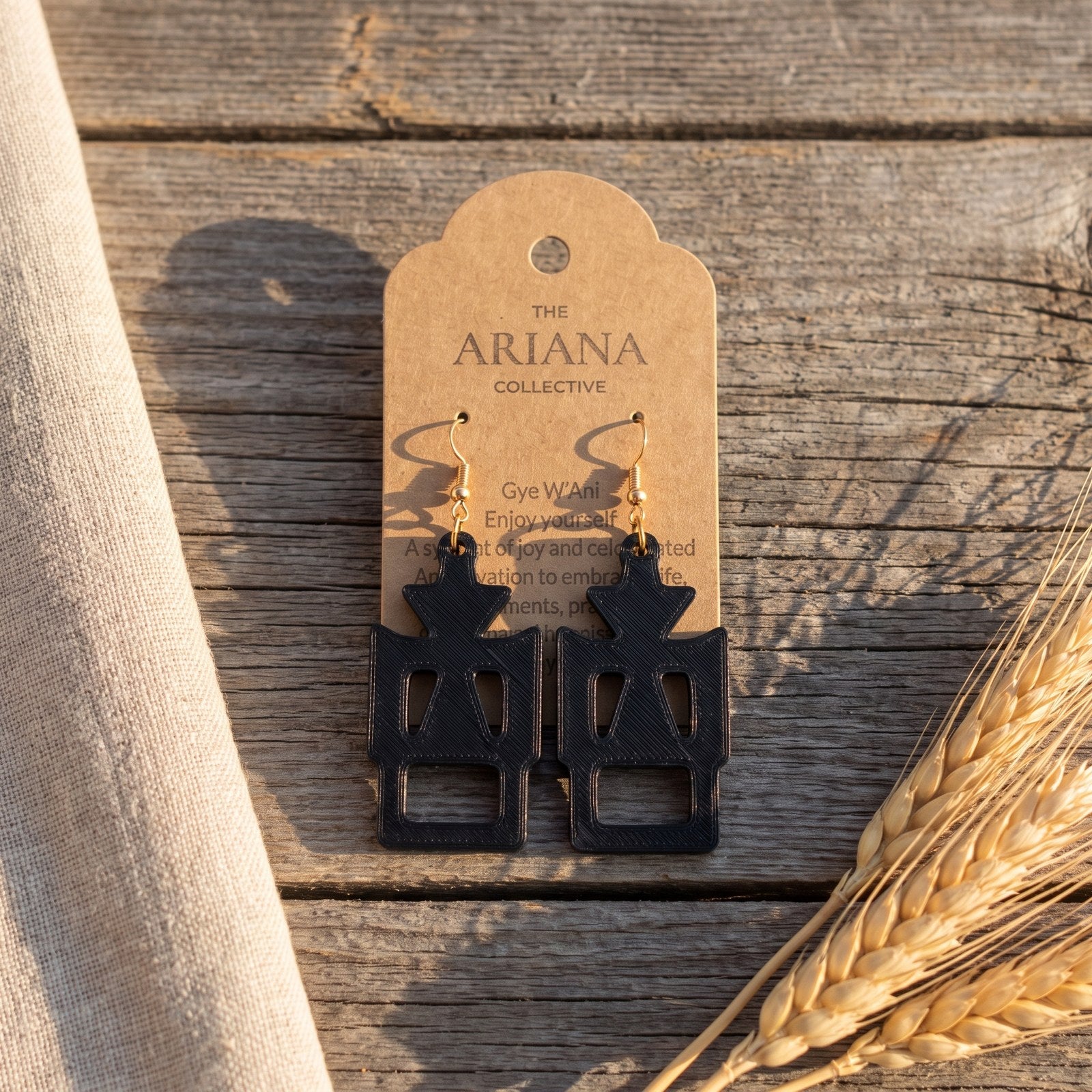 Gye W'Ani Adinkra earrings in black by The Ariana Collective, on a kraft tag