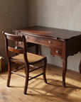 Antique writing desk paired with its cane seat side chair in a corner office setting