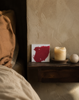 Handmade Artist Painting propped on a nightstand beside a candle in a warm plaster bedroom