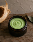 Green Coconut whipped body butter in an amber jar with coconut husk