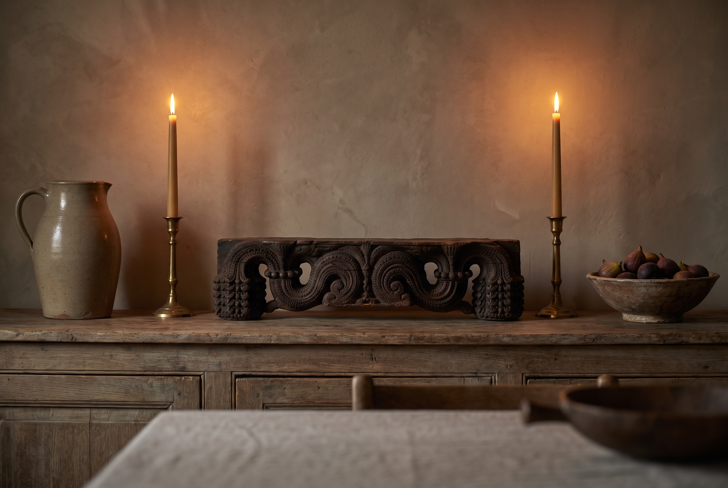 Antique carved wood piece on a dining sideboard between tall candles, showing its small scale