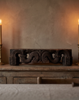 Antique carved wood piece on a dining sideboard between tall candles, showing its small scale