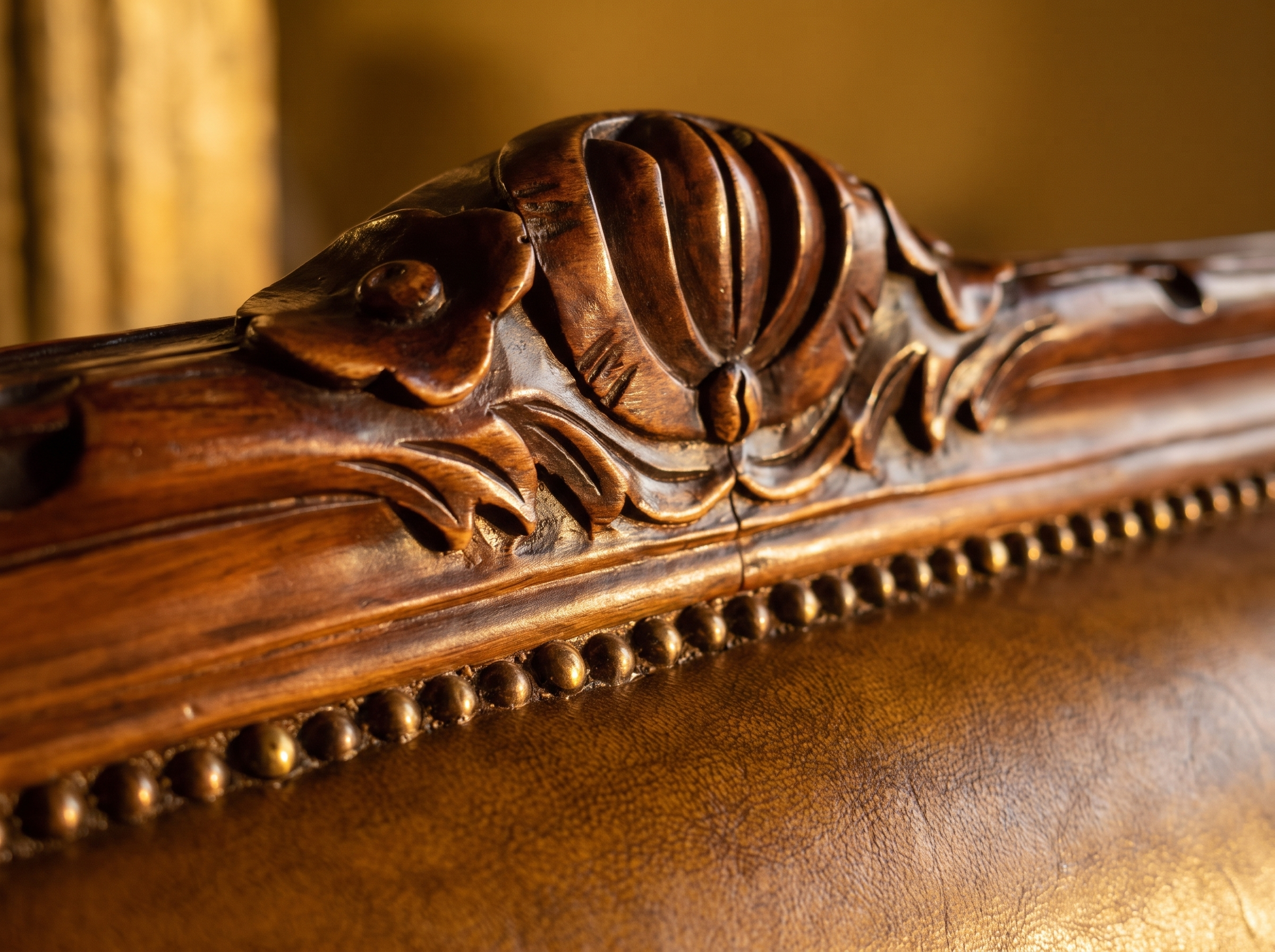 Detail of the hand-carved walnut crest and antique brass nailhead trim