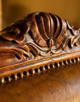 Detail of the hand-carved walnut crest and antique brass nailhead trim