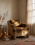 Vintage bronze strié velvet club chair with cream welt, styled in a warm plaster room with candles