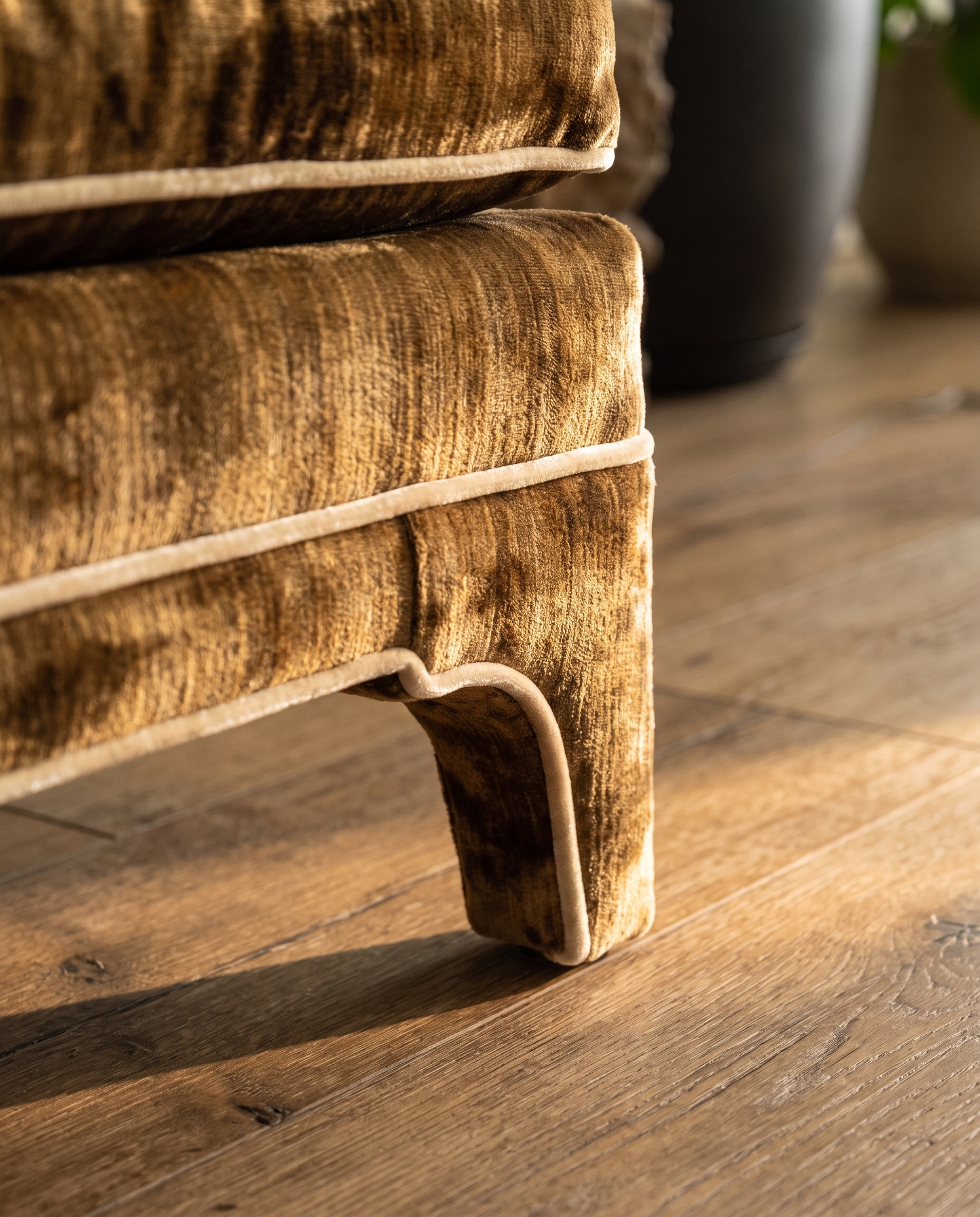 Detail of the sculpted upholstered bracket foot with cream welt