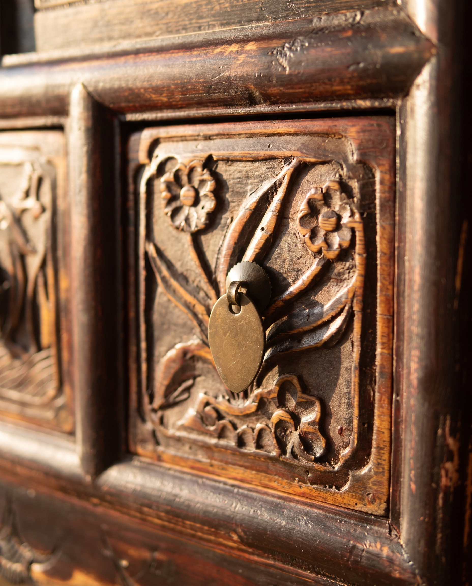 Macro detail of the hand-carved bird and blossom drawer panel with brass ring pull