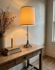 Antique brass table lamp lit and glowing on a rustic console