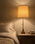Antique brass table lamp lit at the bedside beside linen bedding