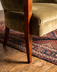 Tapered cherry wood front leg of the chair on an antique kilim rug