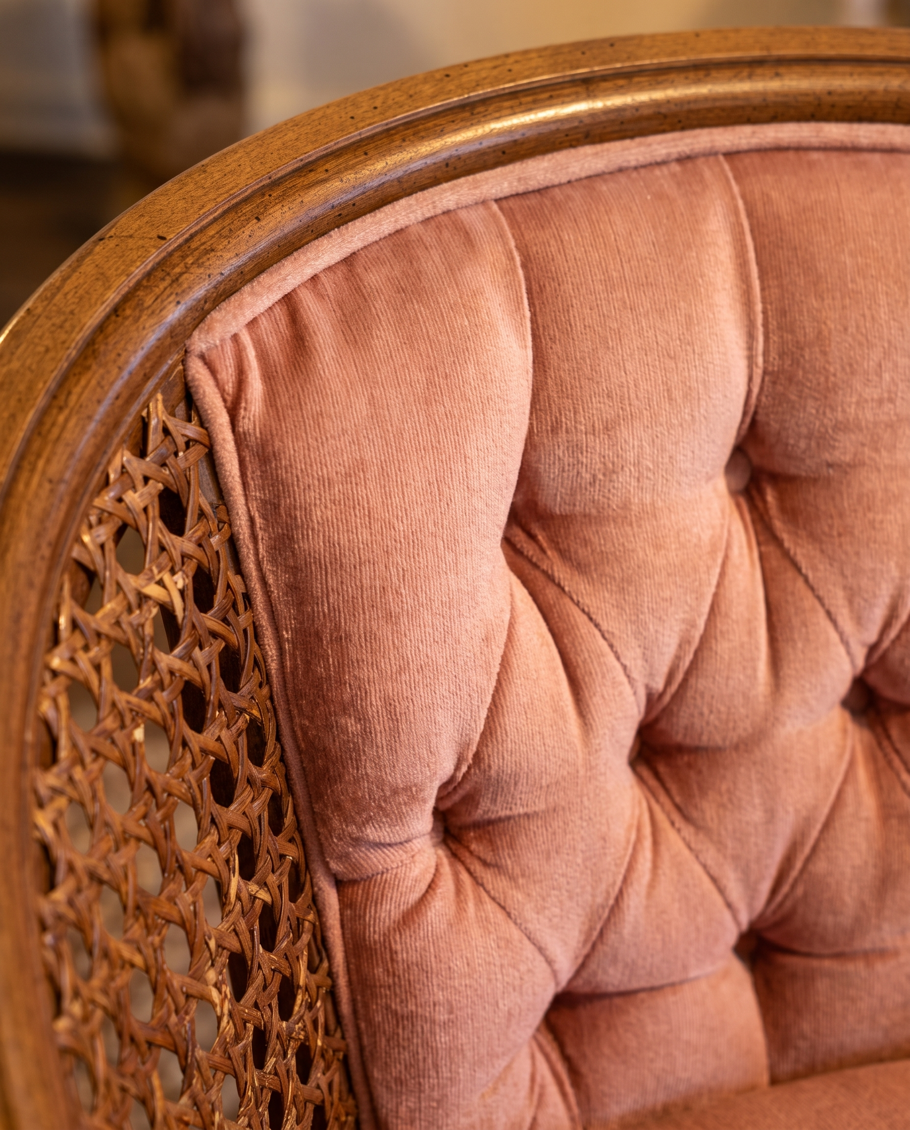 Macro detail of button-tufted rose velvet meeting the woven cane side panel